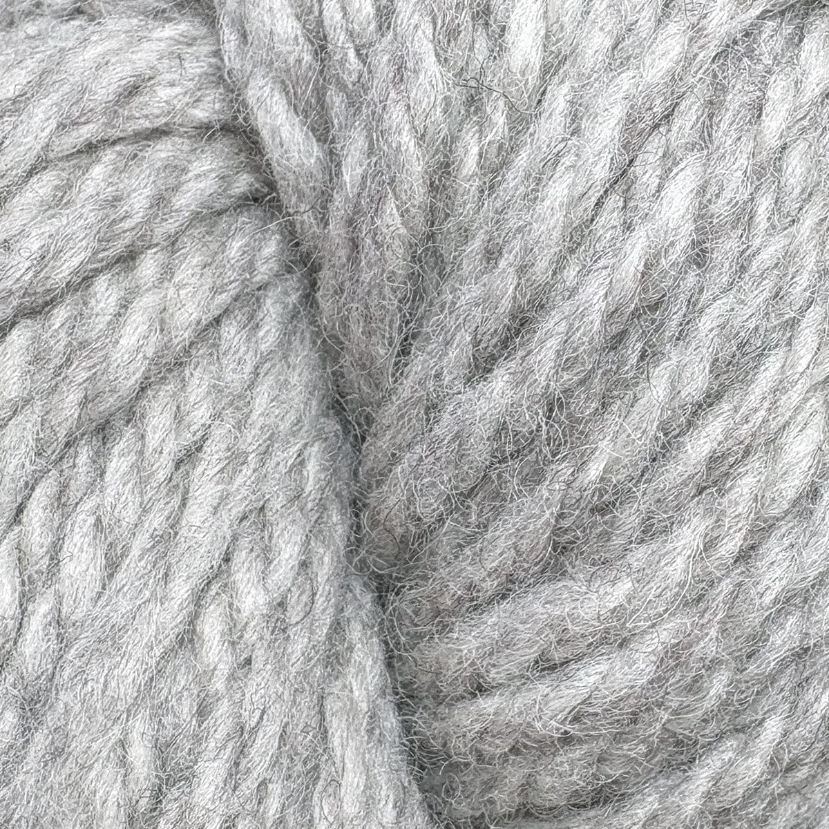Close-up of Halcyon Yarn Classic Rug Wool | Strand by Caledonian Dye Works—light gray skein with thick, soft fibers twisted together, highlighting the detailed texture. Ideal wool for rug weaving projects.
