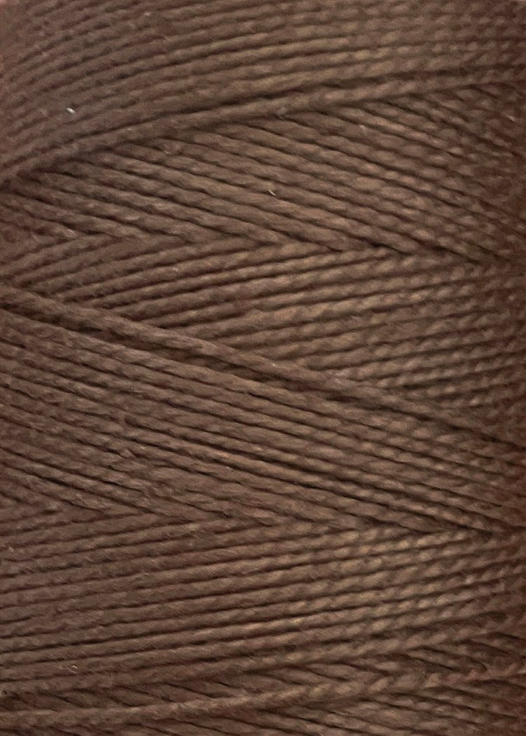 Close-up view of a large cone of Circulo 5/2 Looma Mercerized Pearl Cotton Yarn, highlighting the tightly wound brown strands and the textured surface characteristic of this 100% cotton weaving yarn.