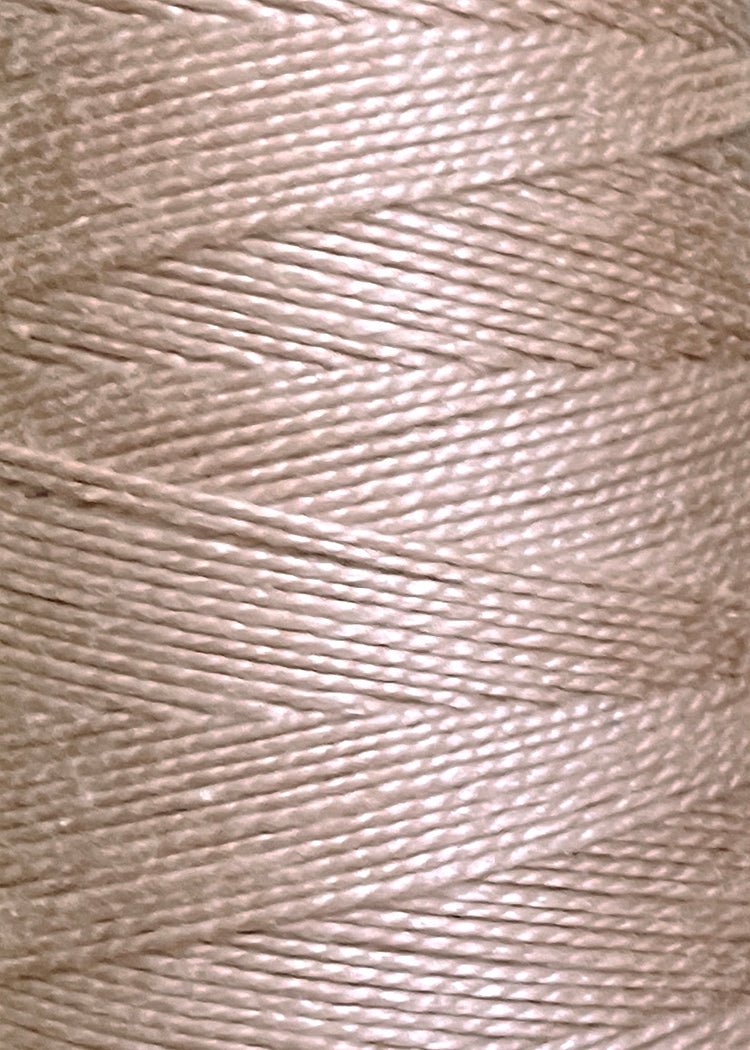 Close-up of 3/2 Looma Circulo Mercerized Pearl Cotton Yarn by Circulo, in beige or light tan, wound tightly in parallel diagonal layers on a mini cone, highlighting the smooth texture and fine fibers of the thread.