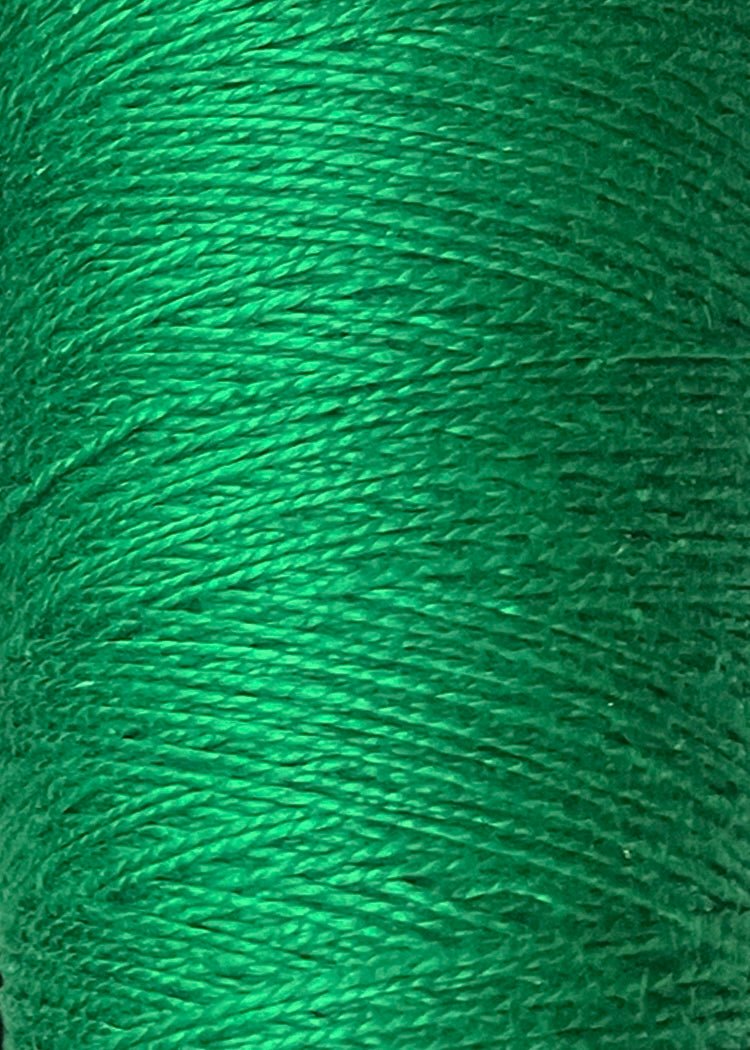 Close-up of a spool of vivid green 5/2 Looma Circulo Mercerized Pearl Cotton Yarn | Mini Cone by Circulo, featuring shiny, tightly wound fibers and intricate texture. This Oeko-Tex certified pearl cotton thread showcases exceptional quality and vibrant color in every strand.