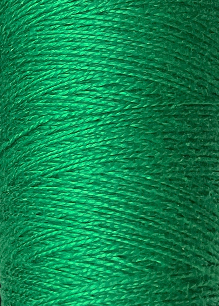 Close-up view of a spool of green 3/2 Looma Circulo Mercerized Pearl Cotton Yarn | Mini Cone by Circulo, highlighting the detailed texture and tightly wound strands of this Oeko-Tex certified cotton yarn.