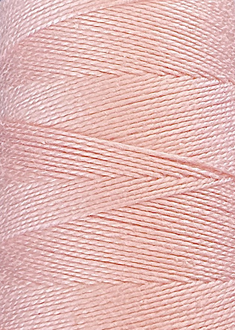 Close-up of a spool of pale pink thread, tightly wound in overlapping diagonal layers, showcasing the smooth and glossy texture of the individual strands—crafted from premium 5/2 Looma Circulo Mercerized Pearl Cotton Yarn | Mini Cone by Circulo.