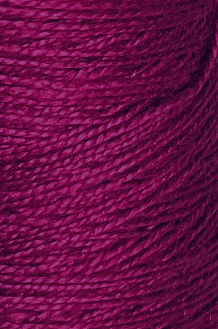 Close-up of textured magenta 3/2 Looma Circulo Mercerized Pearl Cotton Yarn wound in a cylindrical cone, showing detailed fibers and strands of premium weaving yarn from Circulo intertwined closely together.