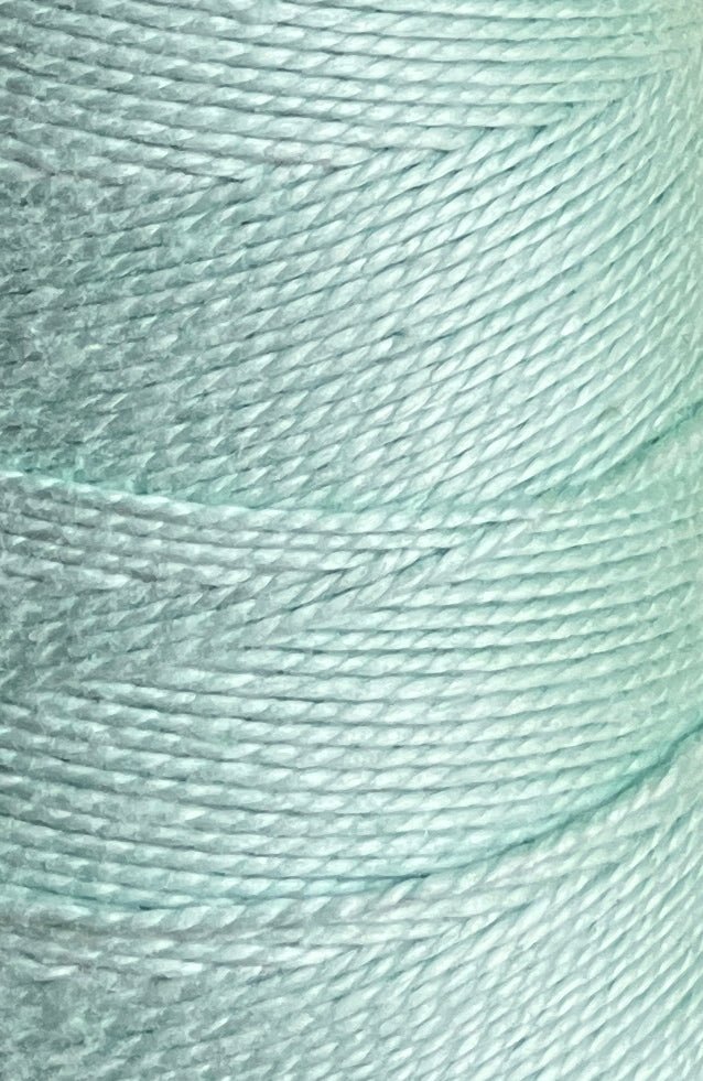 Close-up of Circulo 5/2 Looma Mercerized Pearl Cotton Yarn in light blue, tightly wound in overlapping layers on a mini cone, highlighting the texture and sheen of the individual fibers.