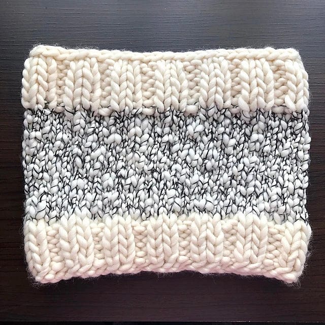 The Aguas Blancas Cowl Pattern by Kristel Nieves for Ravelry Instore features thick cream borders and a textured gray and white marled center, designed for hand-knitting with soft Malabrigo merino wool.