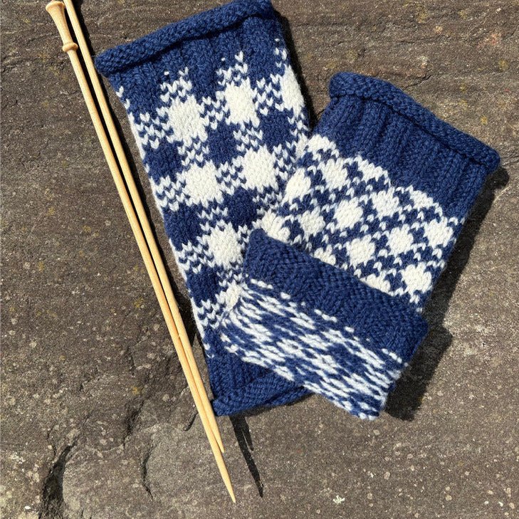 The Cast Off & Cast On: 3-Hour Kennebec Lighthouse & Nature Cruise (August 11) by Halcyon Yarn rests on a stone surface beside three wooden double-pointed knitting needles.