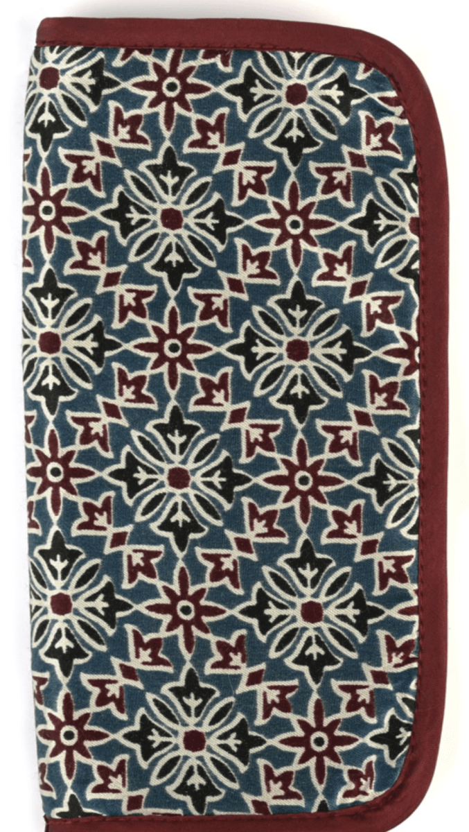 The Lantern Moon DPN Needle Case by Bryson Distributing, Inc. is a rectangular handcrafted case made from IKAT fabric, with a maroon border and geometric floral patterns in maroon, white, and dark green on blue. The wallet stands upright and closed.