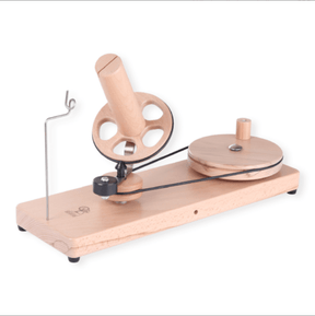 The Ashford Wooden Ball Winder by Ashford Handicrafts Limited features a hand-crank design, rotating handle, circular wheel, tension arm, and sturdy base—ideal for winding yarn into neat balls or cakes.
