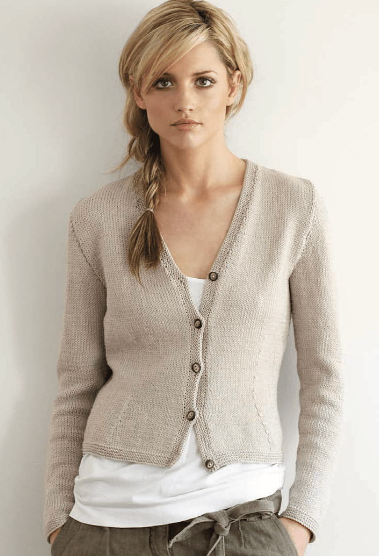 A woman wears a beige, V-neck, ribbed, fitted Fitted Cardigan by Jo Sharp buttoned over a white top.