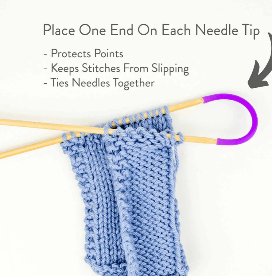 Twice Sheared Sheep’s Tip Ties silicone protectors secure two wooden knitting needles holding blue stitches, shielding tips, preventing stitch slips, and tying needles together. An arrow highlights the stopper in use.