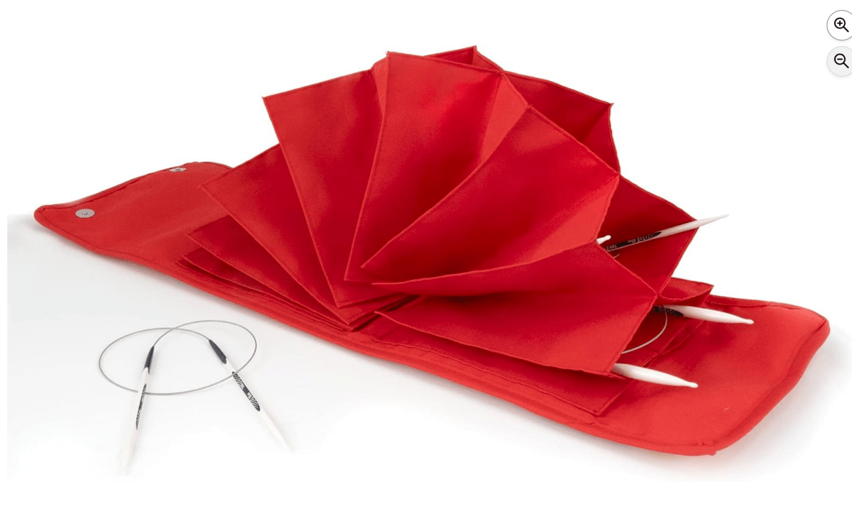 The Bryson Distributing, Inc. Circular Knitting Needle Case is a red organizer with multiple fan-shaped pockets holding needles. Two circular knitting needles with cables and white tips rest on the case.