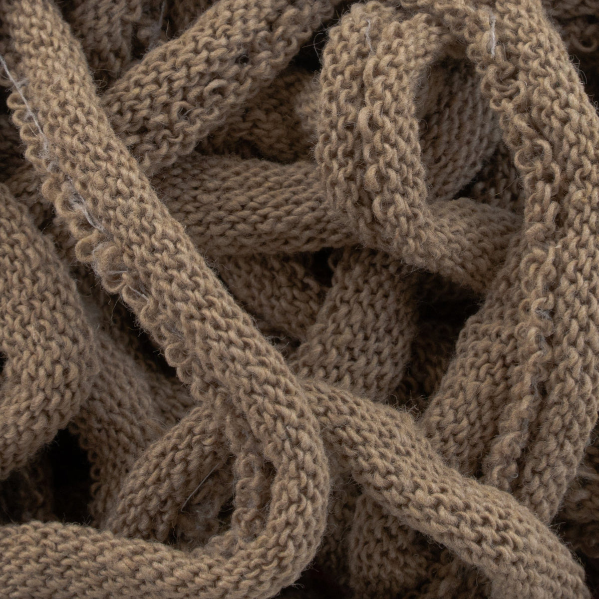 A close-up of interwoven, thick brown Harrisville Potholder Loops by Friendly Loom creates a cozy appearance, reminiscent of patterns crafted on a traditional loom. The design showcases loops and twists, evoking the look and feel of handmade fabric or yarn.