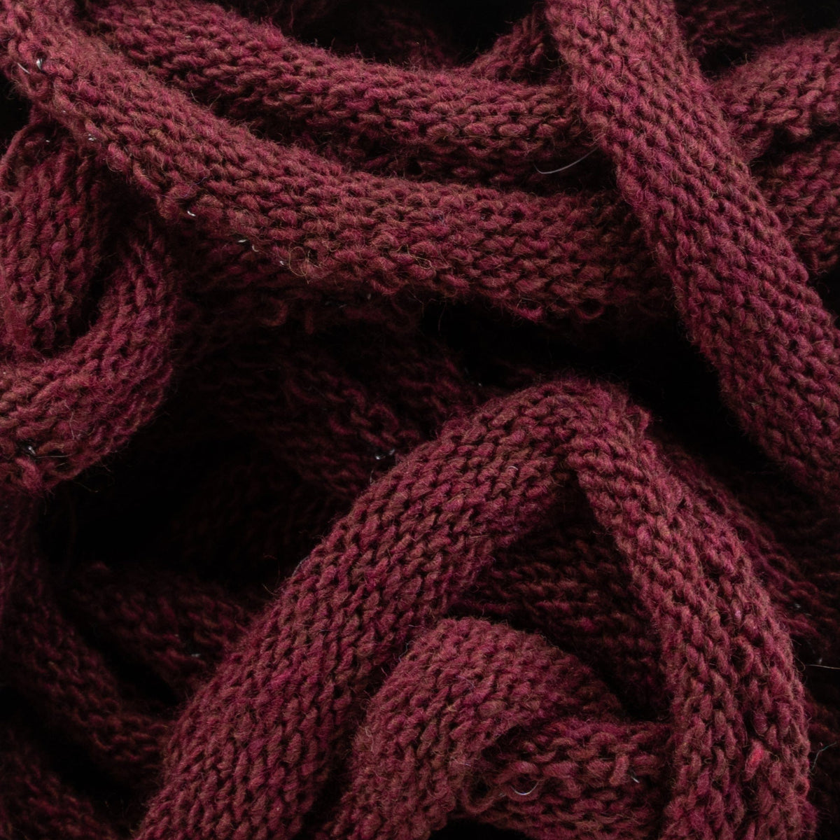 Close-up of intertwined maroon loops crafted using Friendly Loom's Harrisville Potholder Loops in the traditional size, creating a textured pattern. The loops appear soft and thick, showcasing detailed stitching and a rich, deep color.