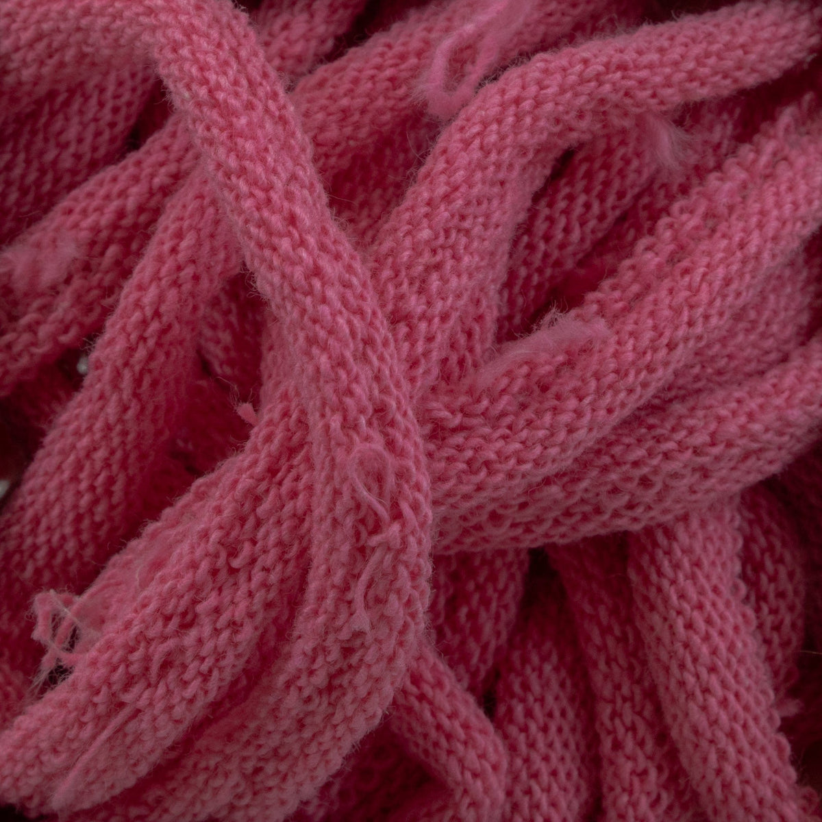 Close-up of tangled pink Harrisville Potholder Loops by Friendly Loom, showcasing their soft texture and intricate weave, reminiscent of the patterns crafted on a traditional loom.