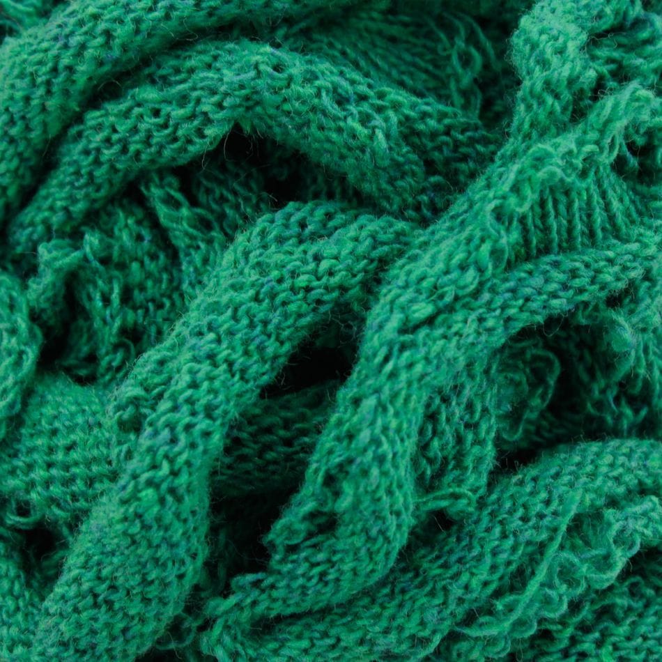 Close-up of a textured, green fabric made with Harrisville Potholder Loops - Traditional Size by Friendly Loom. Crafted using traditional cotton loops, the wavy, intertwined pattern looks soft, featuring visible stitches and folds that create a rich, tactile appearance.