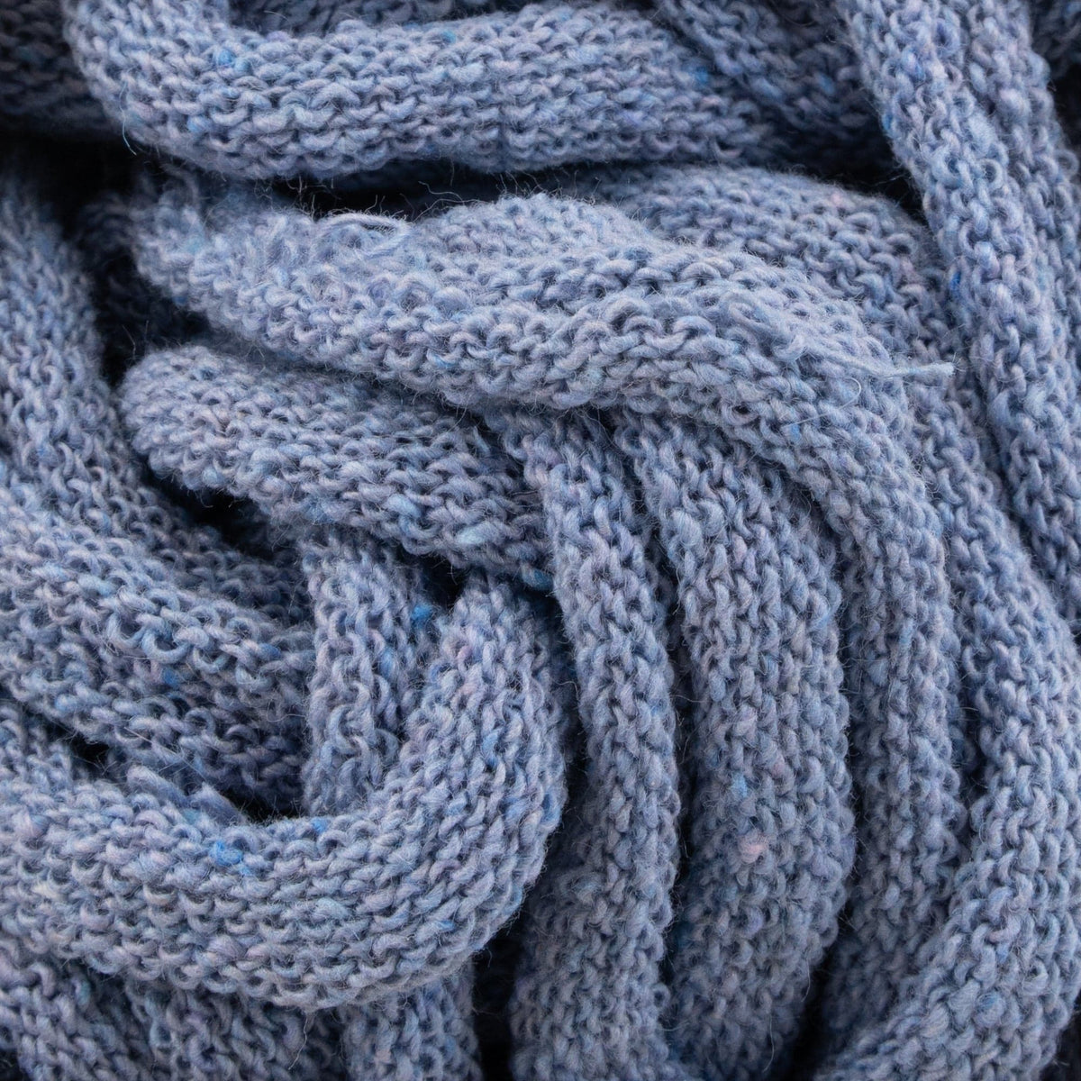 Close-up of blue knit fabric crafted with Harrisville Potholder Loops by Friendly Loom, showcasing a textured pattern and soft, cozy appearance. The cotton loops are intricately woven as if on a traditional loom, creating a sense of warmth and comfort.