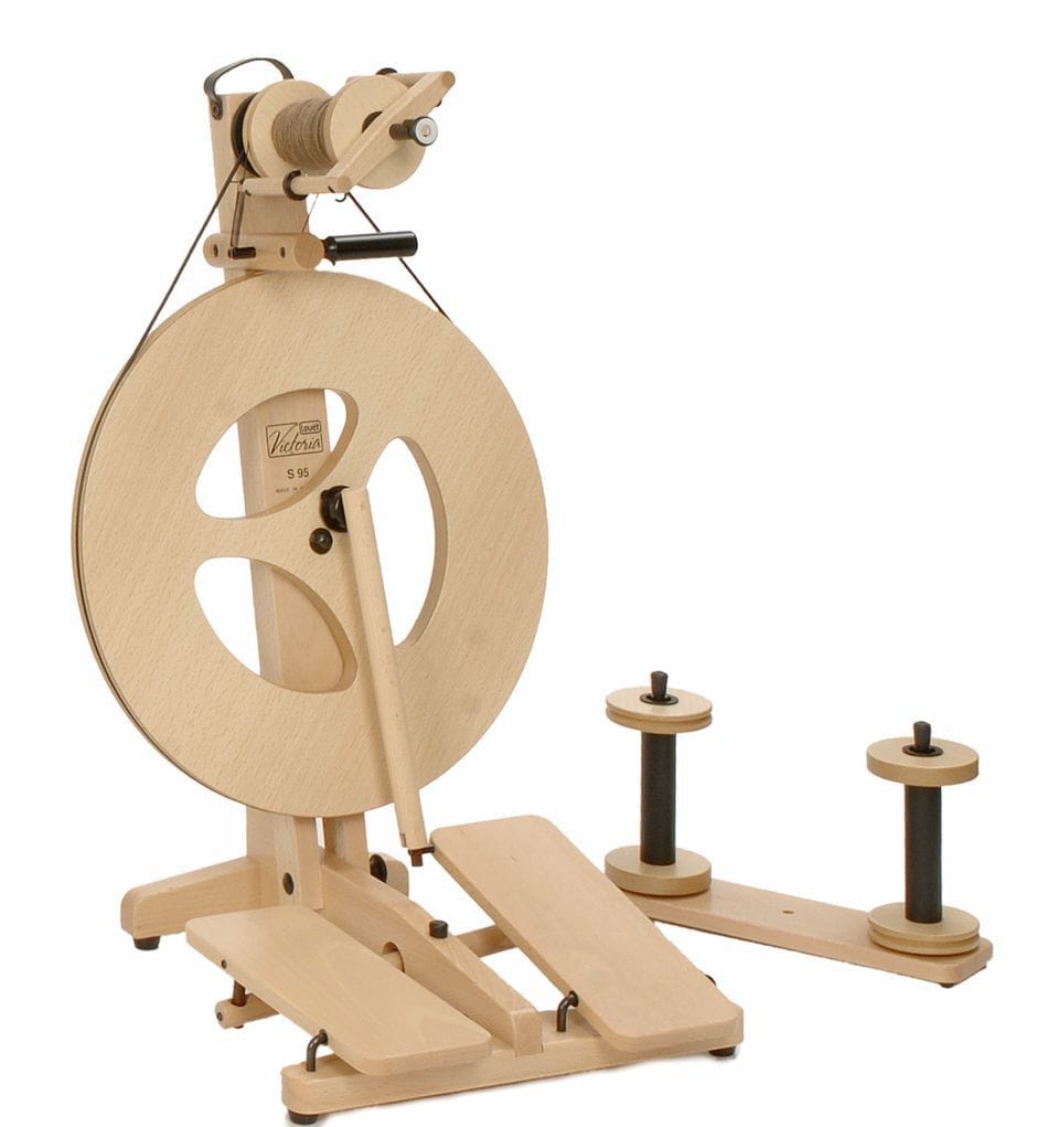 The Louët Victoria Double-Treadle Folding Spinning Wheel, S95 or S96, by Louet Inc., is a portable wooden spinning wheel with a large circular wheel, foot pedals, adjustable bobbin brake, several yarn attachments, double-treadle action, yarn bobbins, and holder.