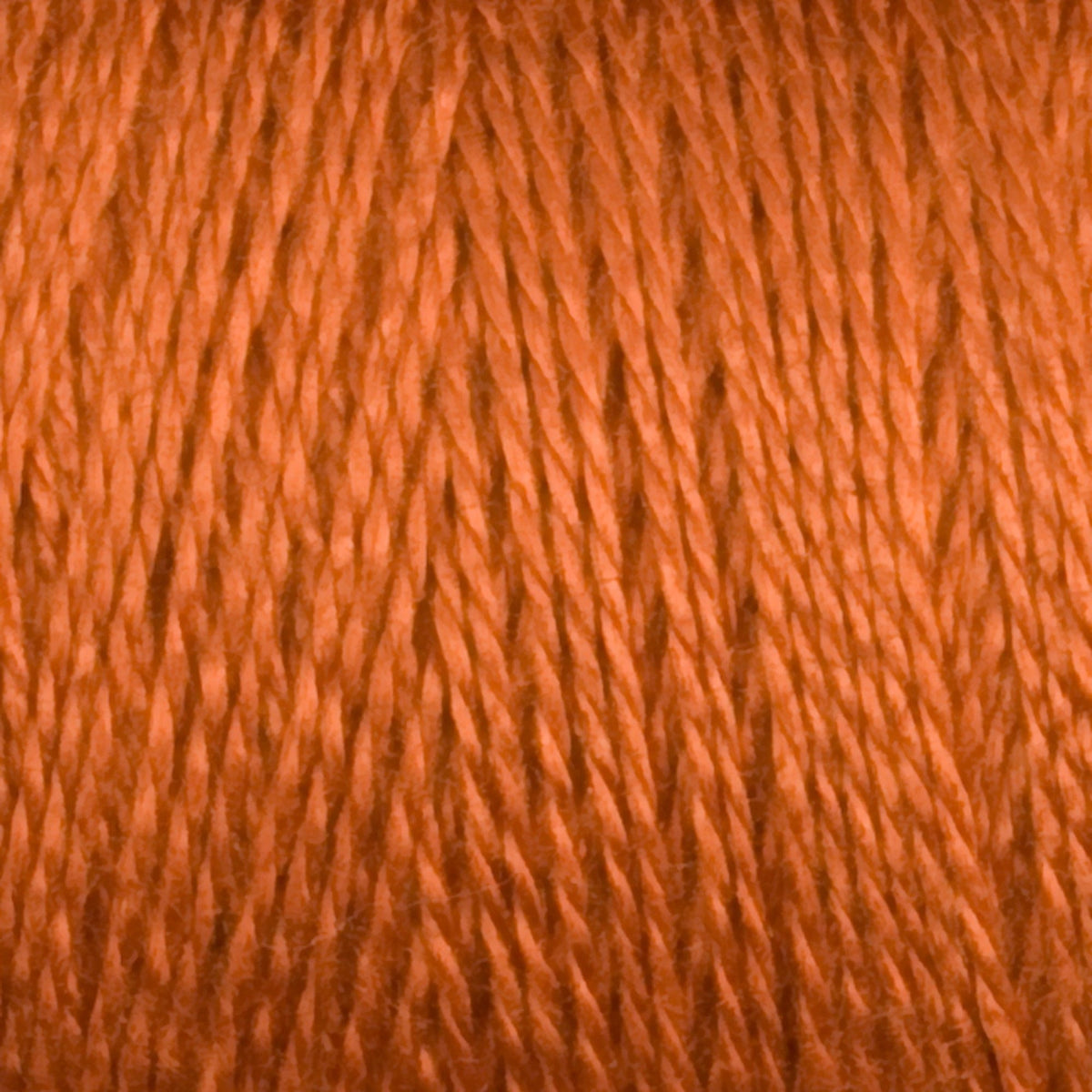 Close-up of Maurice Brassard 8/2 Tencel Yarn on a mini-cone in vibrant orange, showcasing its twisted threads and fibrous texture—ideal for adding bold color to your weaving projects.