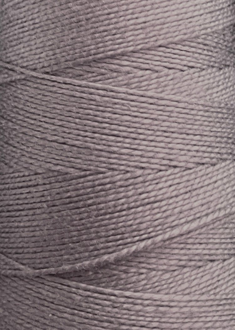 Close-up of a spool of light gray 3/2 Looma Circulo Mercerized Pearl Cotton Yarn | Mini Cone by Circulo, showing tightly wound, textured fibers arranged in a diagonal pattern.