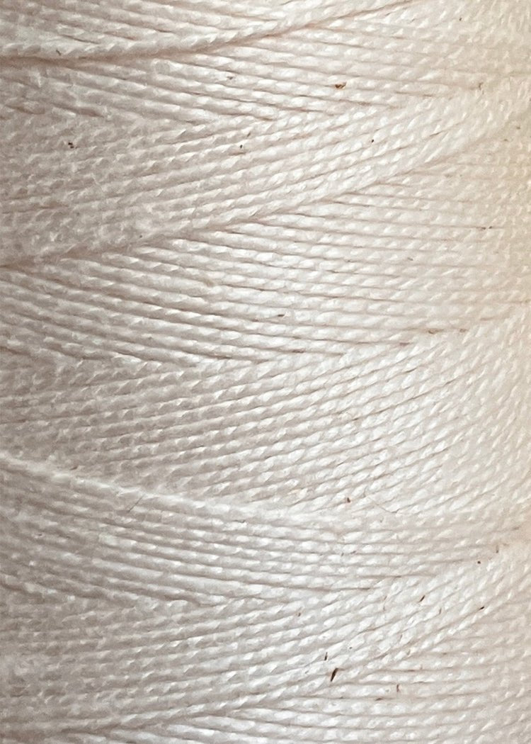 Close-up of white twine or string, such as Circulo's 5/2 Looma Circulo Mercerized Pearl Cotton Yarn in a large cone, wound tightly in parallel rows to highlight the texture and fibers of the material.