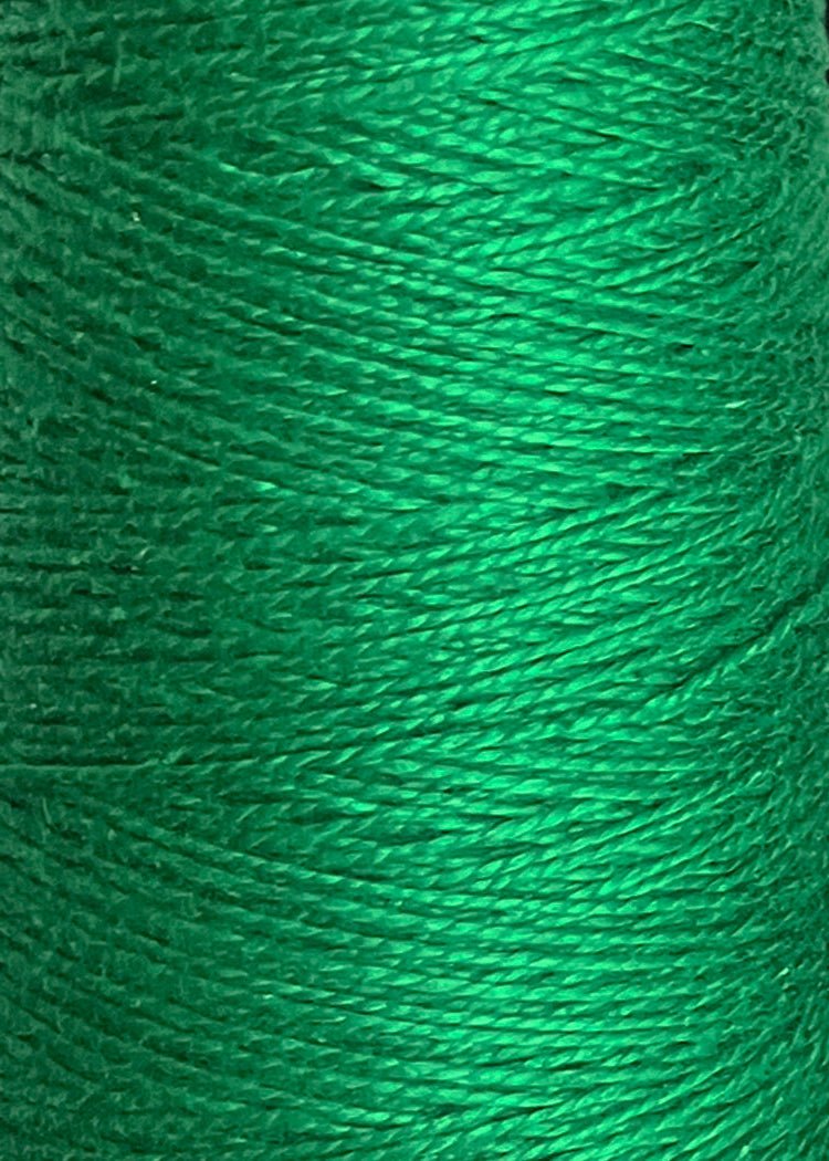 A close-up of a spool of Circulo 3/2 Looma Mercerized Pearl Cotton Yarn in green reveals the finely textured, tightly wound fibers—made from 100% cotton, this large cone of weaving yarn from Circulo offers both exceptional strength and softness.