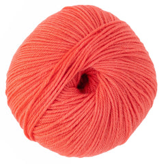 A close-up of Cascade Yarns’ Cascade 220 Superwash Wool Yarn in coral, a DK weight, easy-care yarn with a smooth, soft texture, tightly wound in neat layers and visible center hole.