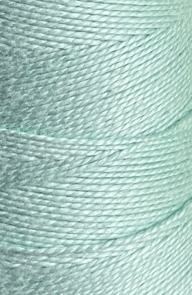 Close-up of a spool of Circulo 3/2 Looma Mercerized Pearl Cotton Yarn in light blue, highlighting the detailed texture and diagonal winding pattern of the fibers on this large cone.