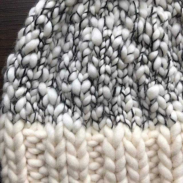 Close-up of the Aguas Blancas Hat Pattern by Kristel Nieves (Ravelry Instore), highlighting chunky white and cream stitches, a ribbed brim, and textured interwoven details.