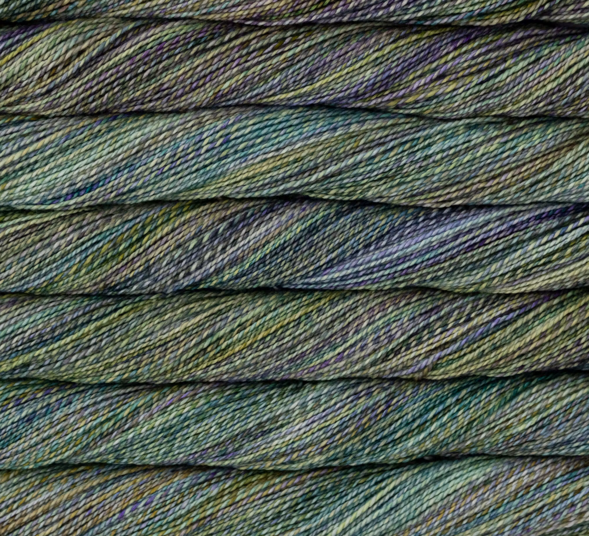 Close-up of stacked skeins of Malabrigo Torzal hand-dyed sport weight yarn in variegated shades of green, purple, and gold.