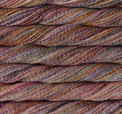 Close-up of stacked skeins of Malabrigo Torzal hand-dyed sport weight yarn in variegated shades of purple, orange, brown, and grey.