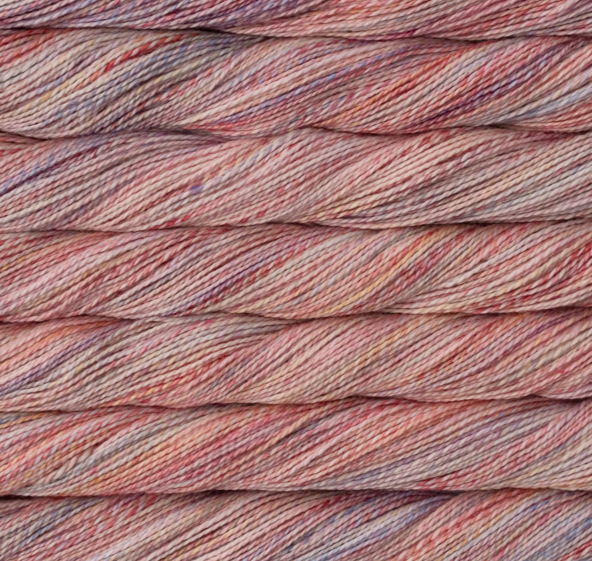 Close-up of a twisted skein of Malabrigo Torzal hand-dyed sport weight yarn in variegated shades of pink, peach, and soft purple.