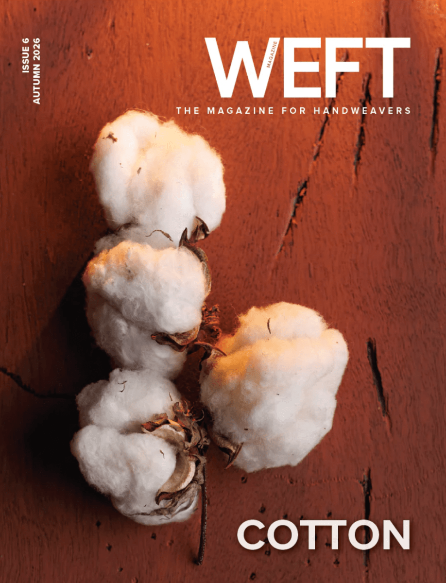 Three fluffy cotton bolls lie on a reddish-brown wooden surface, capturing the enduring heritage of cotton weaving. The title "WEFT - The Magazine for Handweavers, Issue 6, Autumn 2026: Cotton" appears prominently at the top and bottom of the cover, alongside the PLY Magazine brand.