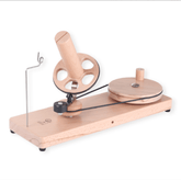 The Ashford Wooden Ball Winder by Ashford Handicrafts Limited features a hand-crank design, rotating handle, circular wheel, tension arm, and sturdy base—ideal for winding yarn into neat balls or cakes.