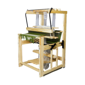 The Glimakra Julia, a compact 4-shaft floor loom by Glimakra, features a counterbalance design with rug weaving threads and partially woven green fabric; levers and pedals are attached, all shown on a white background.