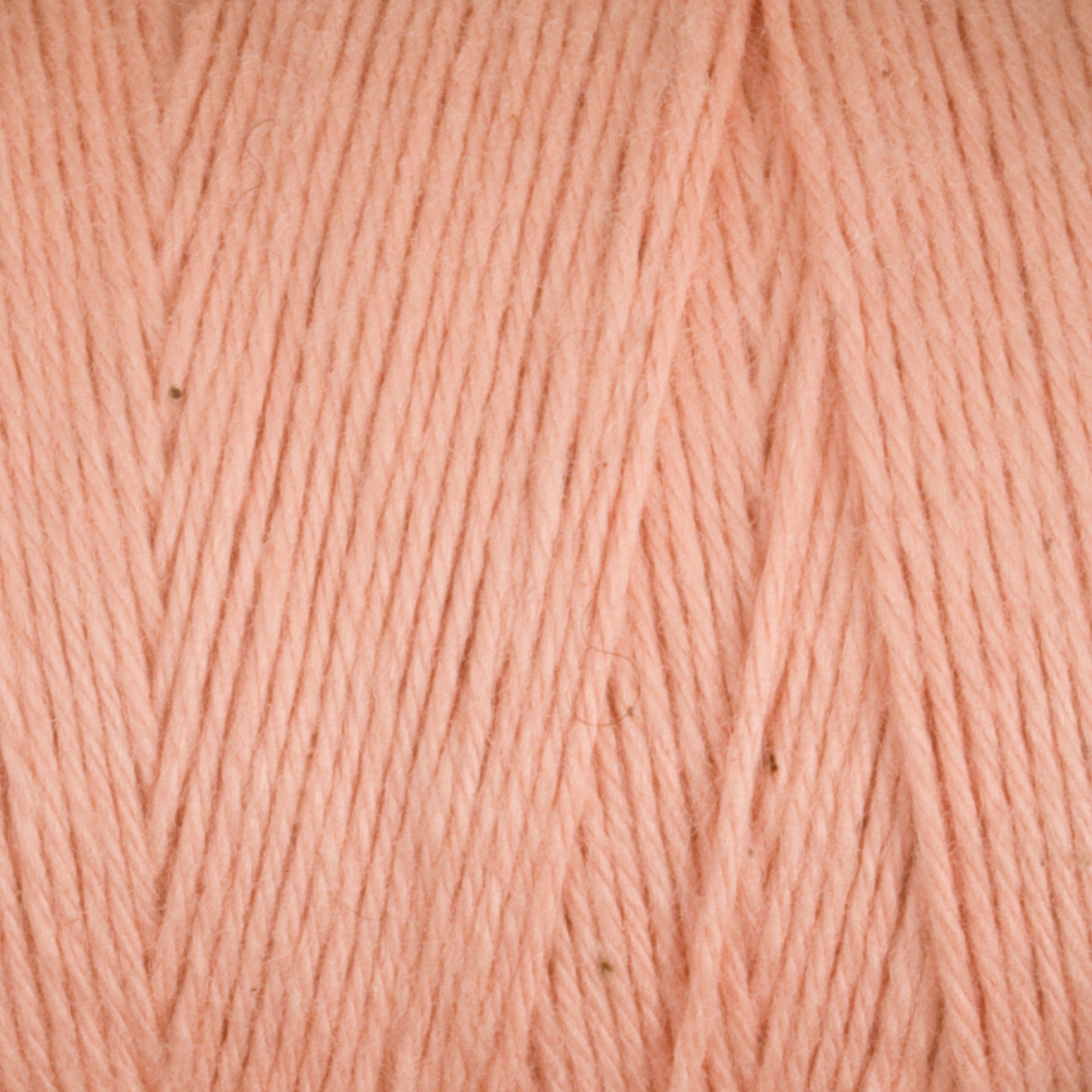 Close-up of soft, pale pink Cotton Carpet Warp 8/4 yarn with a uniform pattern. The colorfast texture features smooth strands and slight hue variations, offering a subtle, natural look similar to cotton warp yarn used for crafting rag rugs.