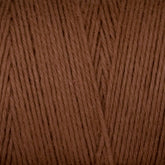 Close-up of Cotton Carpet Warp 8/4 yarn shows tightly wound fibers with a smooth texture. Its warm, earthy tone is colorfast, perfect for knitting or crochet projects like rag rugs due to its perfectly aligned strands.