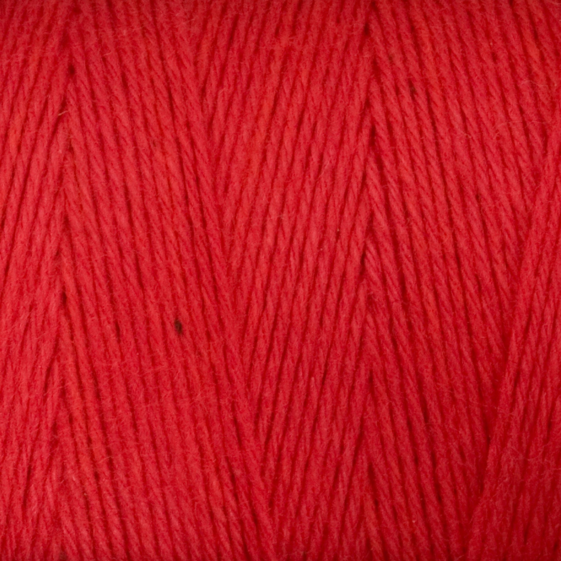 Close-up of Cotton Carpet Warp 8/4 reveals its soft texture and tightly twisted fibers, ideal for rag rugs. The vibrant, colorfast strands display a uniform hue with a diagonal pattern perfect for cotton warp yarn projects.