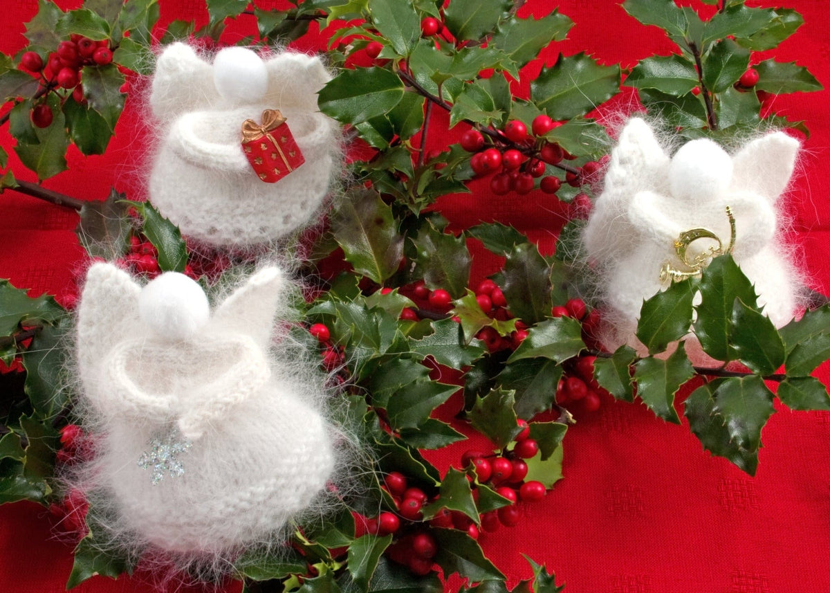 Heavenly Snow Angels, download by Halcyon Yarn features three white knitted angora angels with gifts, horn, and snowflake among holly and berries on red—perfect as charming holiday ornaments.