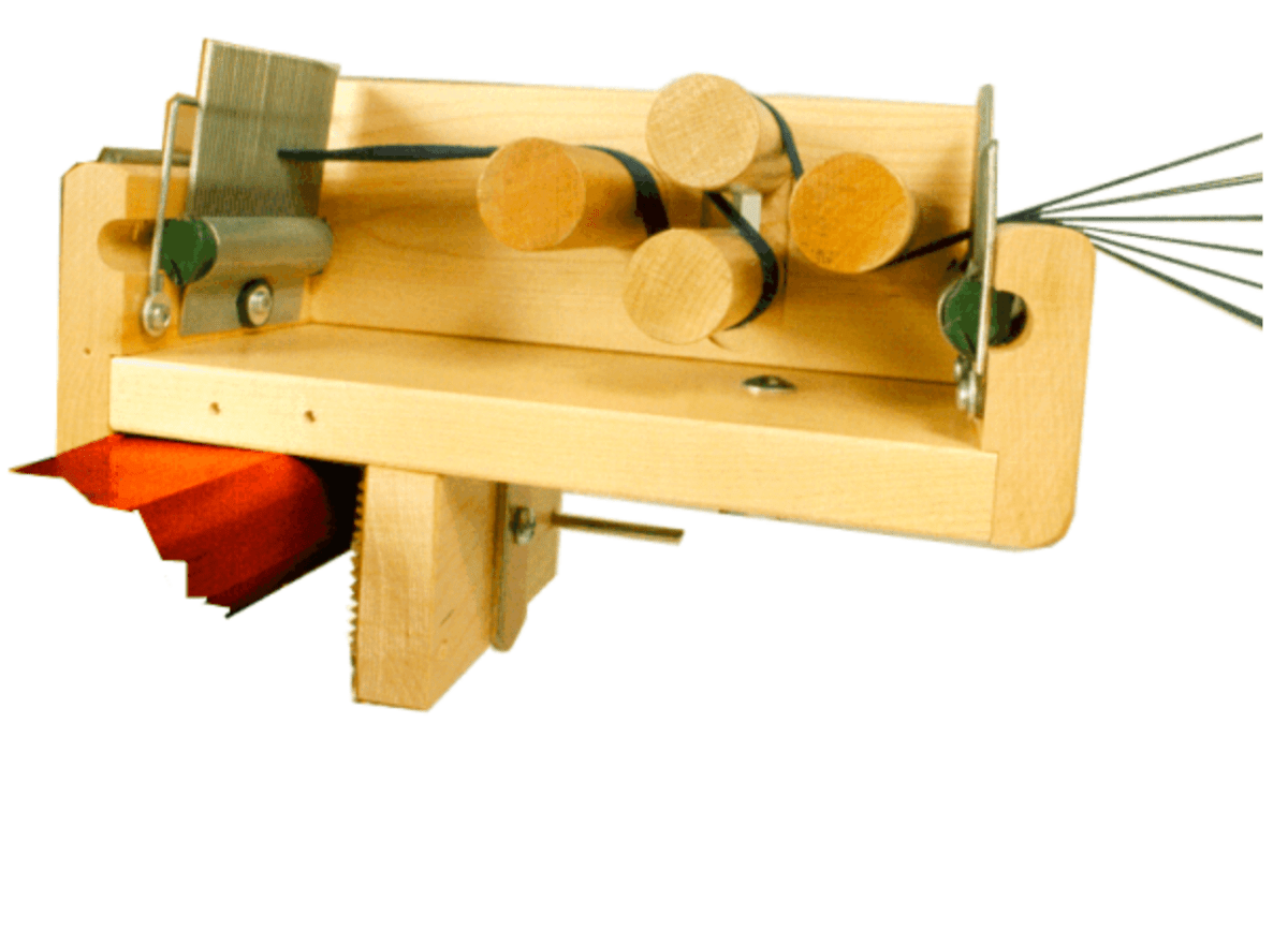 The Leclerc Looms Leclerc Tension Box, featuring cylindrical rollers, metal rods, and a clamp, holds red paper strips and thin wire—ideal for crafting or sectional warping tasks.
