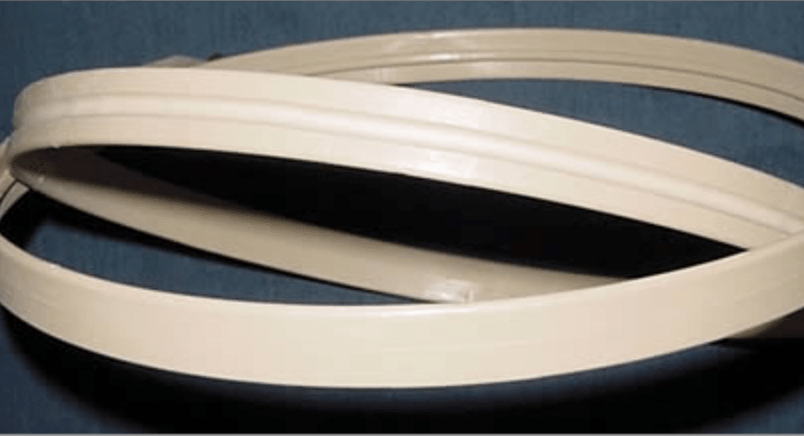 Two beige, flat rubber or plastic Morgan No-Slip Hoops by MQP Distribution, ideal for holding fabric in embroidery projects, are coiled against a dark background.