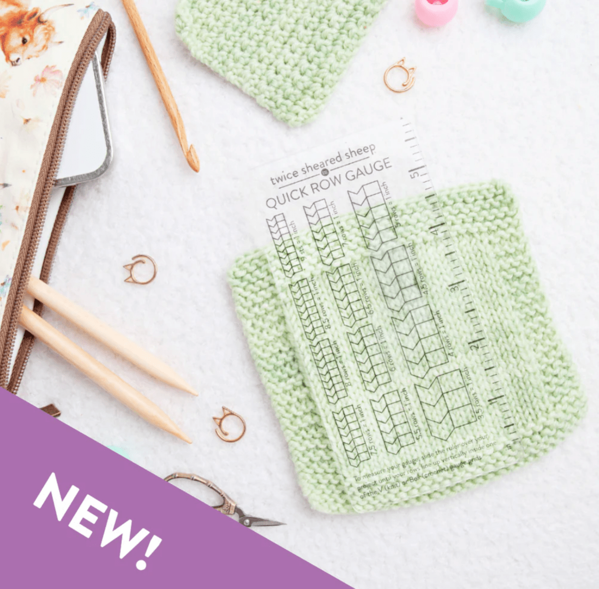 The Twice Sheared Sheep Quick Row Gauge Ruler and tools rest on a light green knit swatch, surrounded by knitting needles, stitch markers, and a floral zip pouch. A purple banner in the corner reads NEW! in white text.