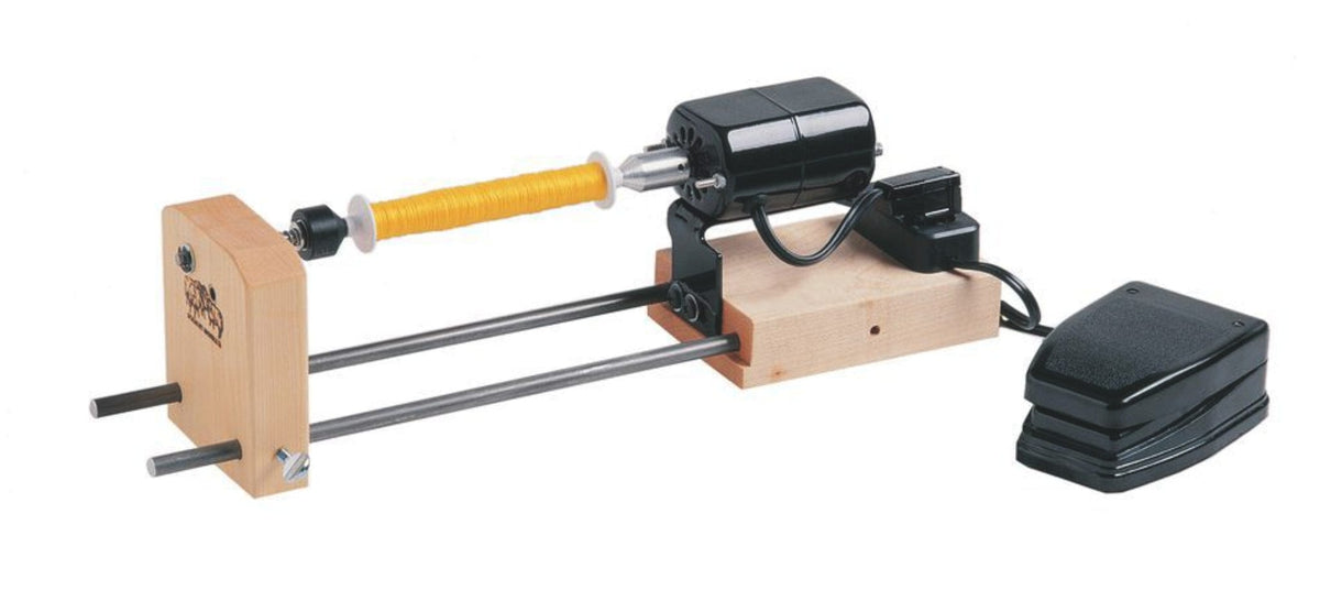 The Schacht Double-Ended Electric Winder by Schacht Spindle Co. features a motorized design, wooden base, foot pedal, and metal rods with a mounted spool of yellow thread, as well as a convenient bobbin winder for efficient thread management.