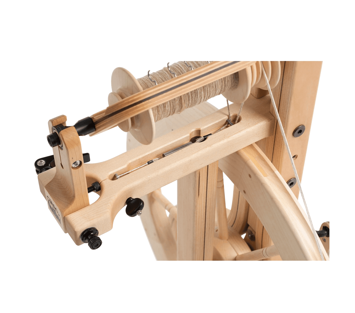 Close-up of the Schacht Matchless Spinning Wheel by Schacht Spindle Co., featuring a double treadle design, smooth finish, and partially wound bobbin that highlights the detailed mechanics of this hardwood spinning wheel.