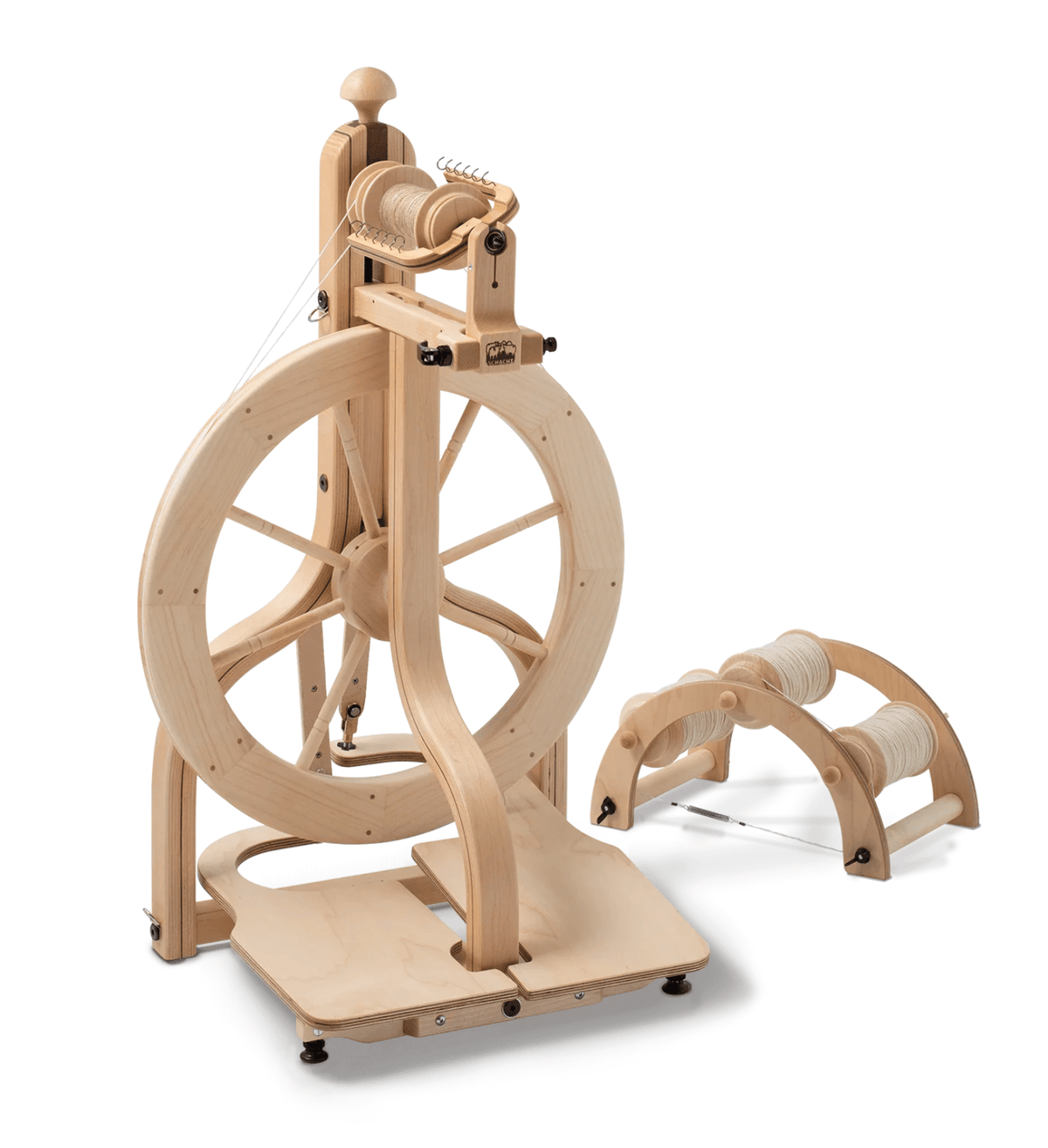 The Schacht Matchless Spinning Wheel, Double Treadle by Schacht Spindle Co. features a large wheel, bobbin and flyer assembly, separate bobbin holder, and includes two spare yarn-wound bobbins set against a light background.