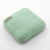 The Woolbuddy Felting Mat, Small is a light green, square 100% wool mat with rounded edges and a woolbuddy tag—ideal for needle felting projects. Shown on a plain white background. Brand: Woolbuddy.