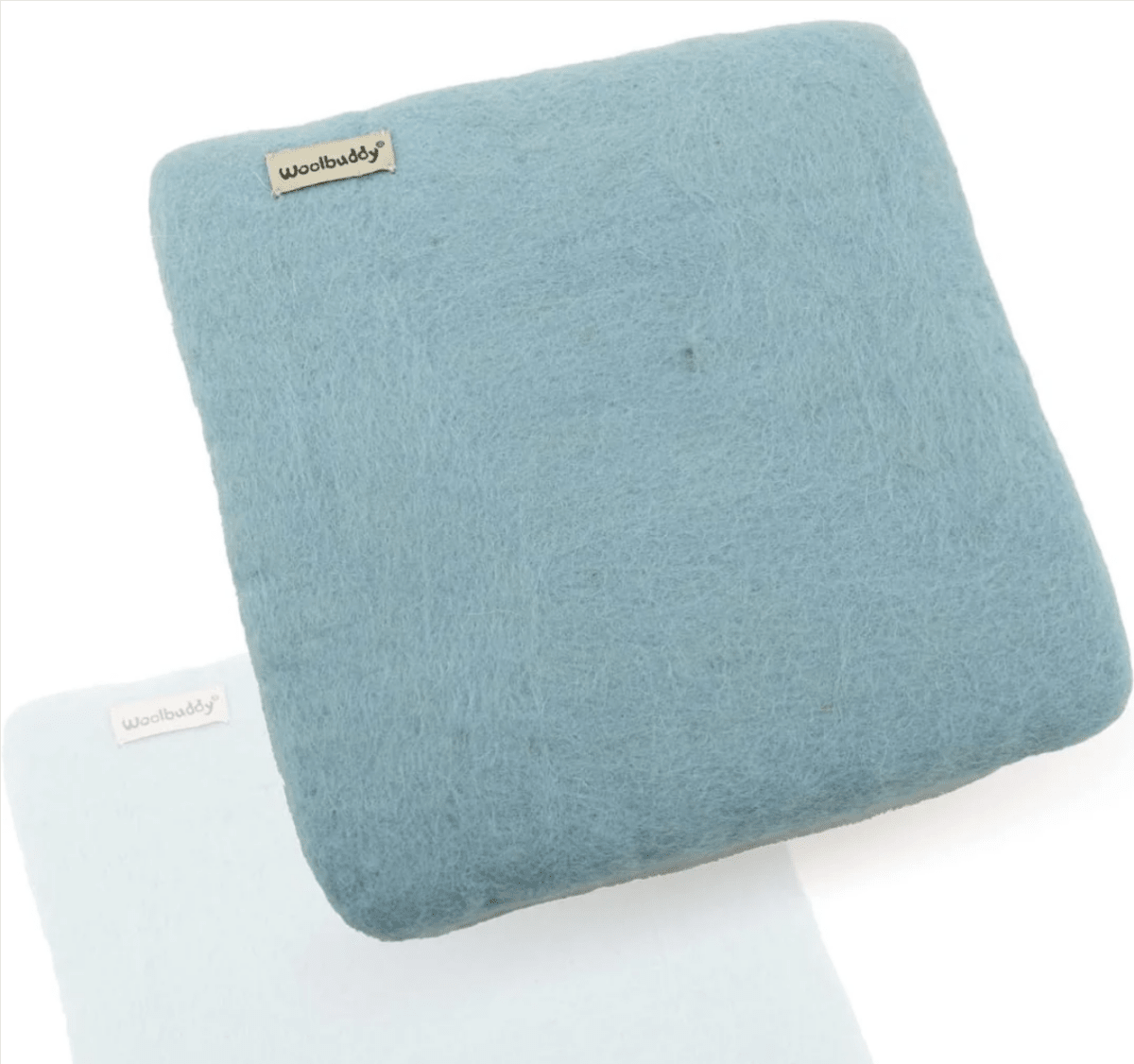 The Woolbuddy Needle Felting Mat Large is a square, light blue wool felt cushion with a small Woolbuddy label in the corner—ideal for wool felting. A lighter-colored mat is partially visible underneath.