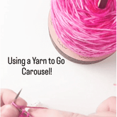 Close-up of hands knitting with pink yarn. A yarn cake rests on the Twice Sheared Sheep Yarn To Go Carousel, Portable Yarn Butler. Text reads: Tangle-free knitting with the Yarn To Go Carousel!.