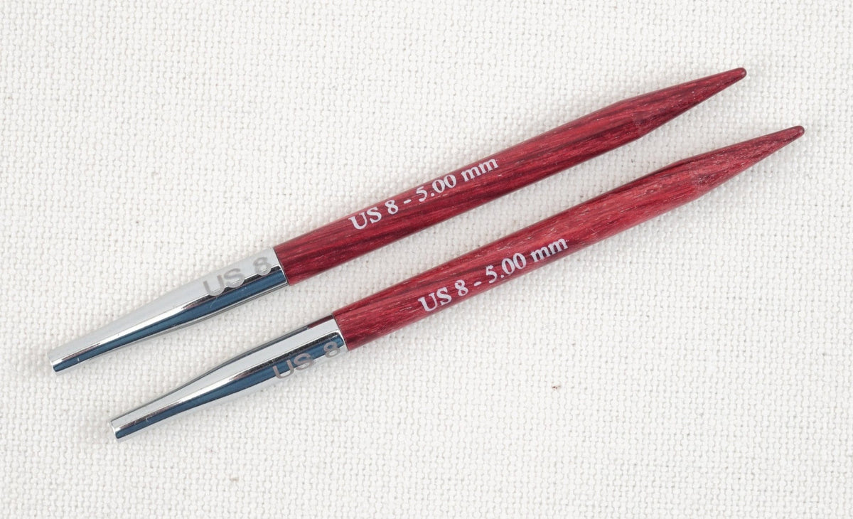 Two Accessories Unlimited Knit Pro (Knitters Pride) Dreamz Interchangeable Knitting Needle Tips, US 8 - 5.00 mm, with metal connectors, are placed parallel on a textured off-white fabric background.