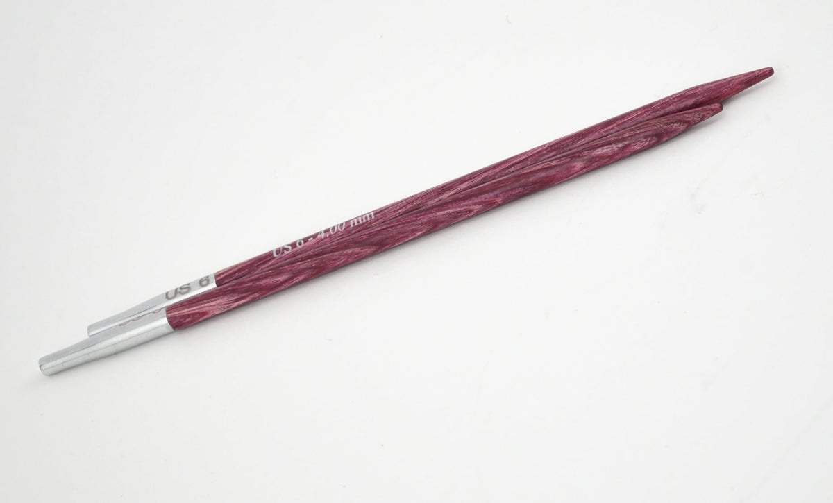 A pair of maroon Knit Pro (Knitters Pride) Dreamz Interchangeable Knitting Needle Tips by Accessories Unlimited, featuring silver ends, lies diagonally on a white surface.
