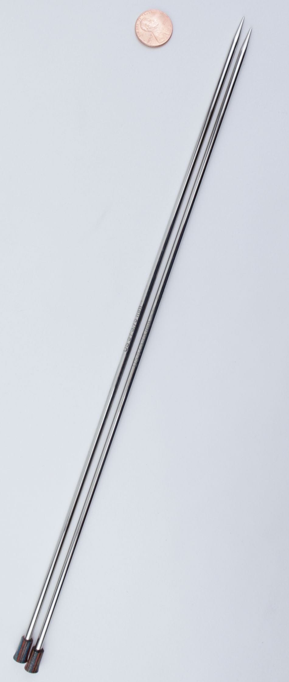 Two Knit Pro (Knitters Pride) Nova Metal Single Point Knitting Needles, 10" or 14" by Accessories Unlimited, with pointed tips and decorative handles, are placed parallel on a white surface next to a penny for size comparison.